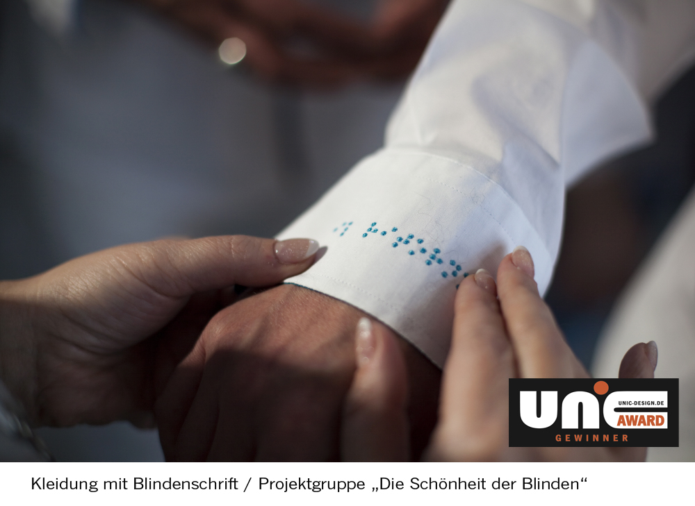 Bild von einer Hand, die das Kleidungsstück für Blinde berührt