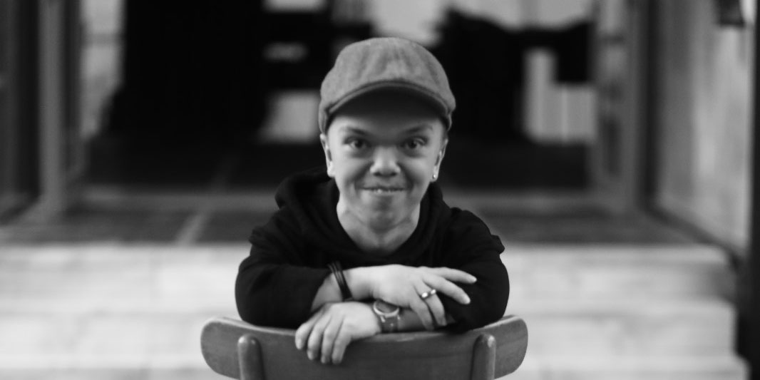 Draußen vor dem Theater. Marvin Löffler trägt Sacko, T-Shirt und Jeans. Er streckt den Daumen nach oben und lacht