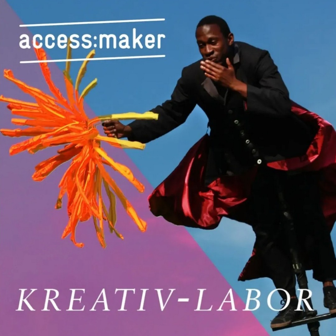 Mann im schwarzen Anzug mit orange-gelber Kunstinstallation; Text „access:maker“ und „KREATIV-LABOR“ im Hintergrund.