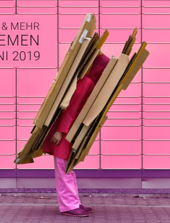 Mensch, eingepresst zwischen Kartons, steht vor einer Mauer. Am Rücken steht: Mittenmang Theaterfestival &amp; Mehr und am Bauch steht: Theater Bremen, 29. Mai – 2.Juni 2019